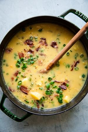 potato and corn chowder with bacon in a stock pot with a wooden spoon