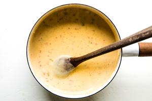 homemade quedo dip in a sauce pan being stirred with a wooden spoon