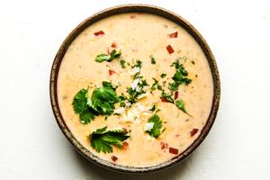 homemade queso dip in a bowl topped with cilantro and diced onion