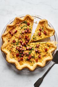 homemade Quiche Lorraine filled with onion, eggs, garlic, cream, salt, pepper, nutmeg, Gruyère and ham topped with chives