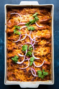 homemade red chicken enchiladas topped with cilantro and red onion