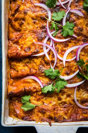 homemade red chicken enchiladas topped with cilantro and red onion