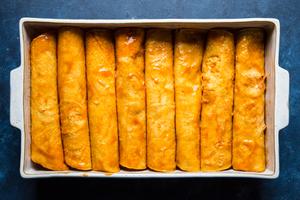 red chicken enchiladas rolled in a baking dish