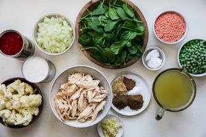 spinach, onion, lentils, peas, chicken, coconut milk, cauliflower, canned tomatoes, coconut oil, spices and broth in bowls