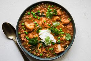A bowl of homemade red lentil soup with chicken, spinach and peas topped with cilantro and greek yogurt