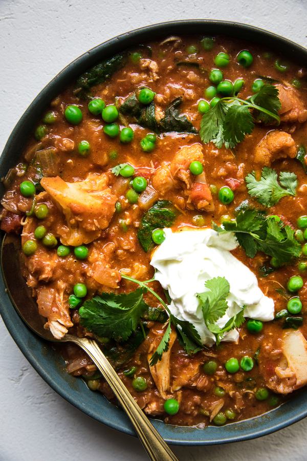 A bowl of homemade red lentil soup with chicken and peas topped with cilantro and greek yogurt