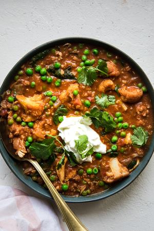 A bowl of homemade red lentil soup with chicken, spinach and peas topped with cilantro and greek yogurt
