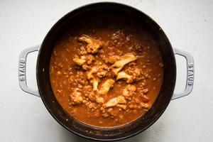 homemade red lentil soup in a pot made with crushed tomatoes, coconut milk, cauliflower, chicken and red lentils