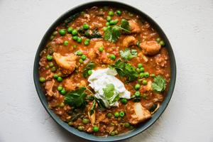 A bowl of homemade red lentil soup with chicken, spinach and peas topped with cilantro and greek yogurt