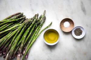 raw asparagus, olive oil, salt and pepper on the counter to make roasted asparagus