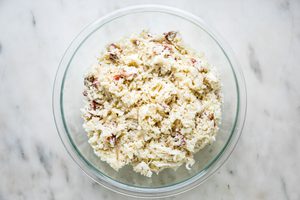 grated potatoes and onion, bacon, gruyere, parmesan, butter, salt, pepper, and nutmeg, greek yogurt and dijon in a glass bowl