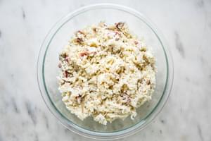 grated potatoes and onion, bacon, gruyere, parmesan, butter, salt, pepper, and nutmeg, greek yogurt and dijon in a glass bowl