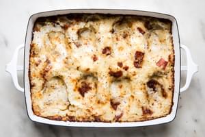 baked potato rösti mixture in a baking dish with indents made by a spoon