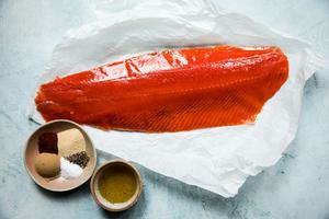 ingredients laid out for baked salmon: raw salmon, olive oil, brown sugar, salt, paprika, garlic powder and pepper