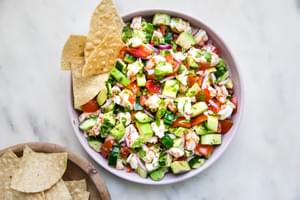 homemade ceviche in a bowl made with shrimp, limes, tomatoes, cucumbers, red onion, cilantro, cayenne, cumin and avocado.