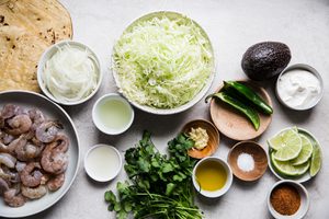 ingredients laid out to make shrimp tacos with cabbage slaw and avocado crema