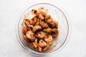 a bowl of raw shrimp marinating in olive oil, lime juice and taco seasoning to use for shrimp tacos