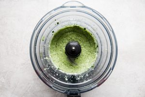 smooth avocado crema in a food processor made with jalapeno, sour cream, cilantro and lime juice