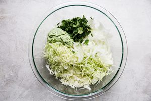 ingredients for cabbage slaw being tossed in a bowl to put on top of juicy shrimp tacos
