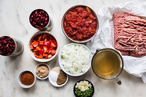 ground beef and pork, veggies, spices, kidney beans, canned tomatoes and chicken stock on the counter to make simple chili
