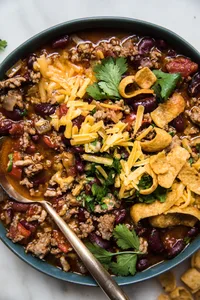 homemade simple chili in a bowl topped with cheddar cheese and green onion