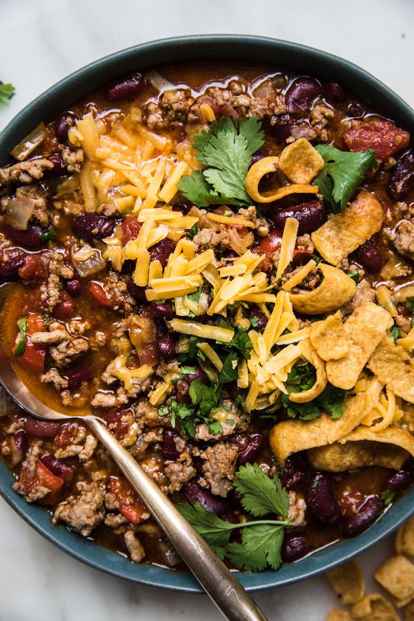 homemade simple chili in a bowl topped with cheddar cheese and green onion