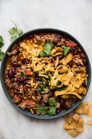 homemade simple chili in a bowl topped with cheddar cheese and green onion