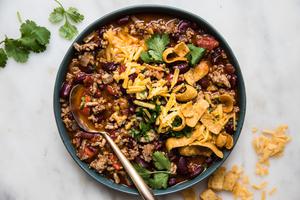 homemade simple chili in a bowl topped with cheddar cheese and green onion