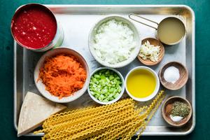 tomatoes, spaghetti, onions, carrots, celery, olive oil, chicken broth, spices and chicken broth in bowls on the counter