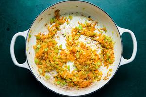 chopped carrots, celery and onions being sautéed in olive oil in a pot