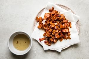 cooked bacon on a paper towel lined plate and a bowl of reserved bacon grease