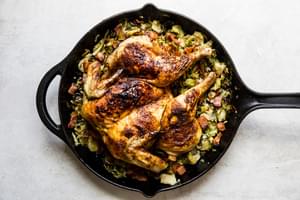 spatchcocked roast chicken on top of shaved brussels sprouts in a cast iron skillet