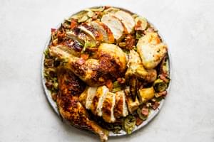 sliced spatchcocked roast chicken on top of shaved brussels sprouts on a serving platter