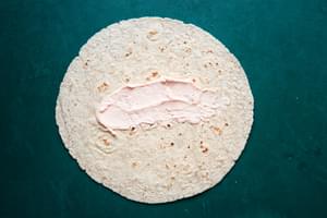 tomato cream cheese spread on a whole wheat tortilla
