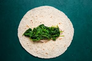 whole wheat tortilla with tomato cream cheese and cooked spinach