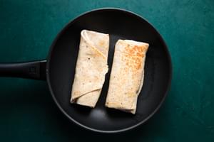 spinach feta wraps filled with tomato cream cheese, sun dried tomatoes, feta and scrambled egg whites being grilled in a pan