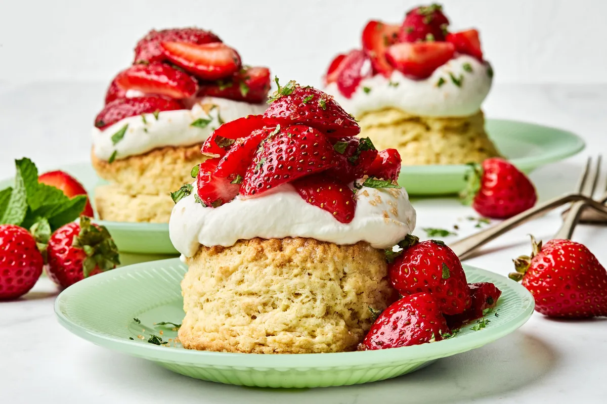 Homemade strawberry shortcake topped with fresh sliced strawberries and fluffy whipped cream, served on a flaky biscuit