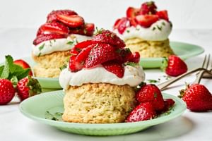 Homemade strawberry shortcake topped with fresh sliced strawberries and fluffy whipped cream, served on a flaky biscuit