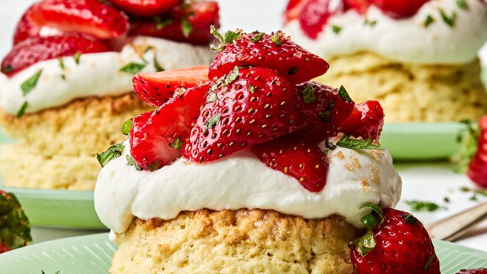 Homemade strawberry shortcake topped with fresh sliced strawberries and fluffy whipped cream, served on a flaky biscuit