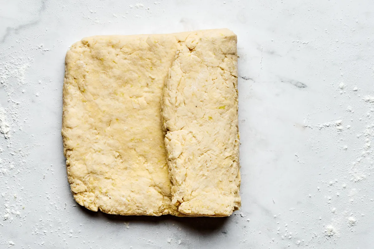homemade biscuit dough being pressed a folded to prepare for strawberry shortcake