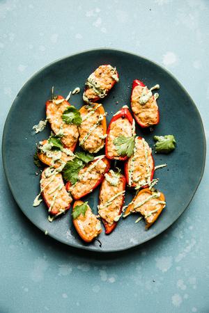 Stuffed Mini bell Peppers on a plate with avocado cream and cilantro