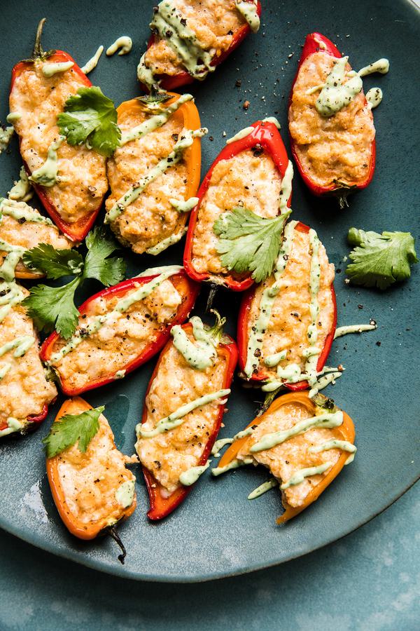 mini bell peppers stuffed with cheese and cream cheese baked in the oven with an avocado pipping sauce and cilantro