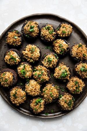 Stuffed Mushrooms made with cream cheese, Parmesan and spices topped with toasted breadcrumbs and parsley on a serving plate