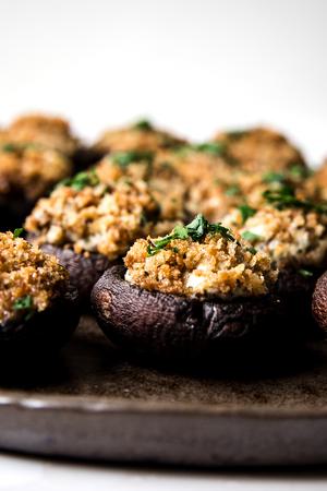 Stuffed Mushrooms made with cream cheese, Parmesan and spices topped with toasted breadcrumbs and parsley on a serving plate