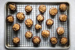 raw stuffed mushrooms topped with toasted panko breadcrumbs on a wire cooking rack inside a baking sheet