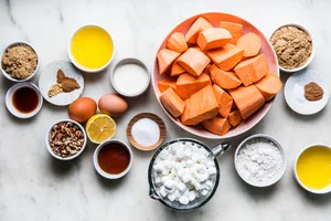 ingredients for sweet potato casserole with marshmallows and pecan streusel in bowls on a counter