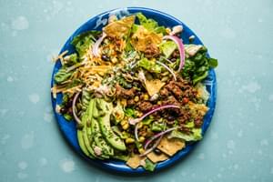 homemade taco salad recipe with corn, beans, tortilla chips, avocado and sour cream