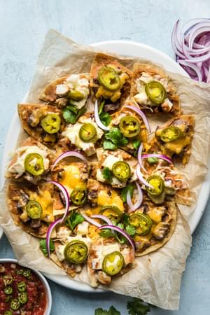 homemade Texas nachos on a platter garnished with pickled jalapeños, red onions and cilantro
