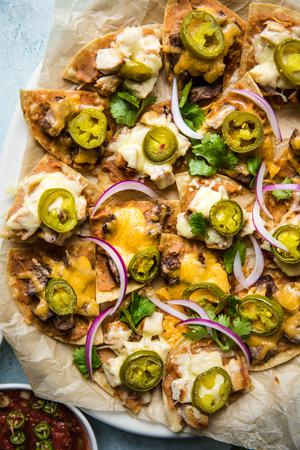 homemade Texas nachos on a platter garnished with pickled jalapeños, red onions and cilantro