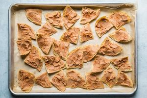 chips with refried beans on a baking sheet